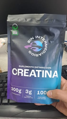Cliente sosteniendo el empaque negro y azul del suplemento Creatina Monohidrato.
