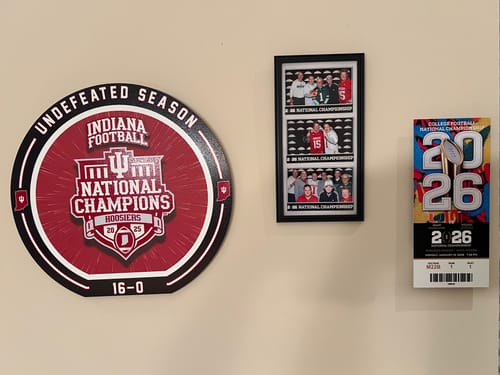 Customer's personalized ticket stub metal wall art displayed on a wall with a round Indiana Champions sign.