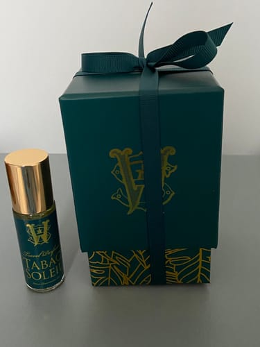 Customer's travel size Tabac Soleil bottle with a gold cap next to its dark green gift box.