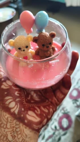 Reviewer holding the large Sweetheart Jar Candle. The cute candle has two teddy bears and balloons inside the pink wax.