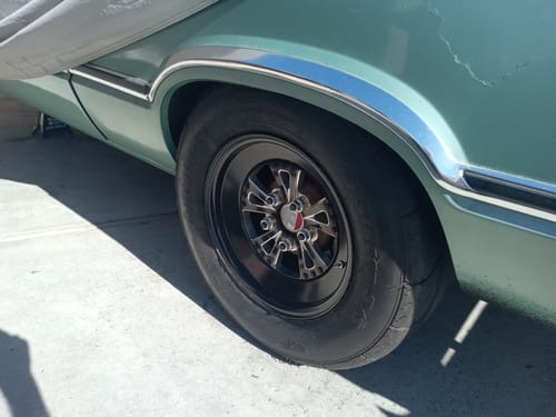 Customer's Steel Lugnut Kit installed on the black and chrome rear wheel of a classic car.