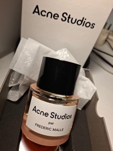 Recensore mostra il flacone dell'eau de parfum Acne Studios appena aperto nella sua confezione.