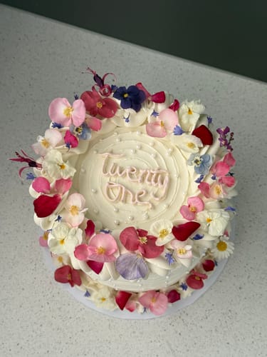 Customer's top-down view of a beautiful white birthday cake decorated with colorful Rainbow Flowerfetti.