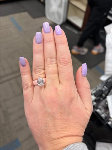 Customer's hand wearing the pear-cut CZ silicone ring from the GlowStone Collection with lavender-painted nails.
