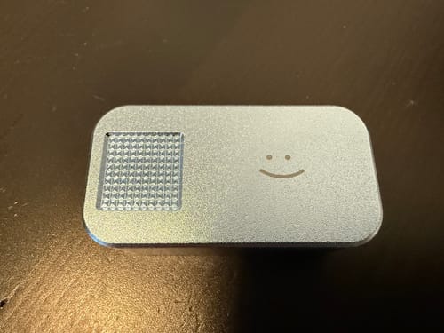 Customer's silver metal pill case from the 2-Pack Bundle, showing the textured grip and smiley face on the lid.