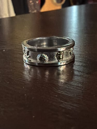 Customer's chunky PSYCHEDELIC LOVE RING with raised symbols sits on a dark table.