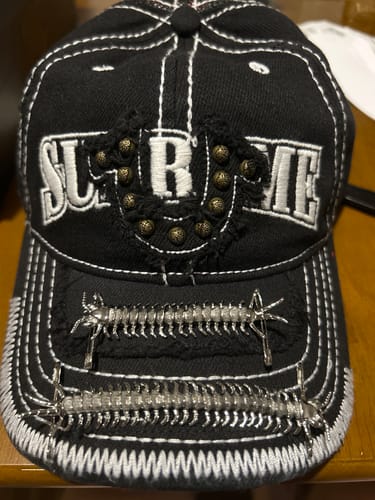 Customer showing two silver Centipede Safety Pins attached to the brim of a distressed black cap.