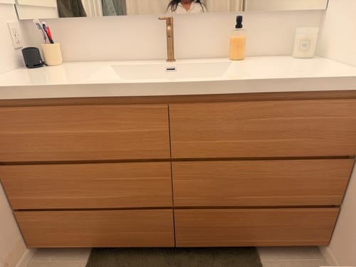 Customer's Monterey Modern Vanity in a light wood finish with a white integrated sink top, installed in a bathroom.