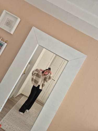 Kundin trägt den gestreiften Bold Stripes Oversized Cardigan zu einer schwarzen Hose in einem Spiegelselfie.