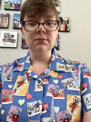 Reviewer wearing the blue 'Picture Perfect' shirt, showing the detailed pattern of Gonzo and Camilla snapshots.