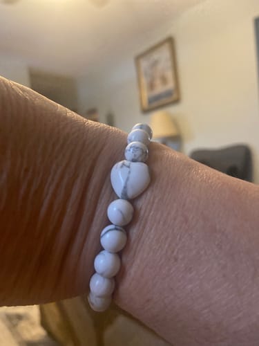 Close-up of a reviewer wearing a white Howlite bracelet with a heart-shaped bead.