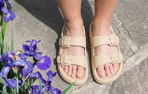 Customer wearing the beige Vibe sandals with two adjustable buckles on a stone patio.