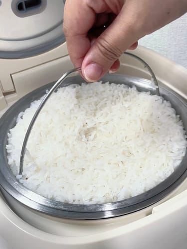 Customer lifting the inner basket of fluffy white rice from the Eurohauz Healthy Rice Cooker.