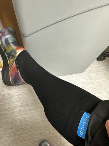 Customer's leg wearing the black Performance Eucalyptus Compression Sock with a multi-colored shoe.