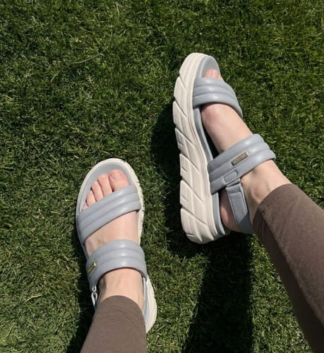 Reviewer wearing the supportive, light blue Align sandals with chunky white soles on a grassy lawn.