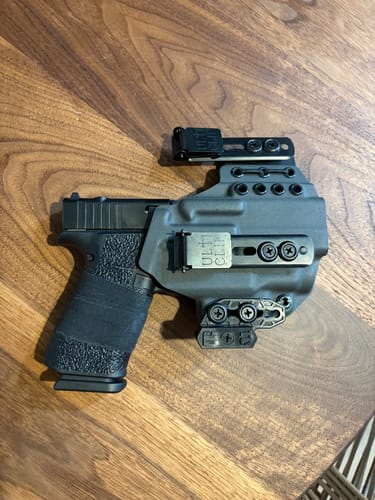 Customer's dark gray XIPHOS ELITE holster with a handgun inside, showing its adjustable clips on a wooden surface.