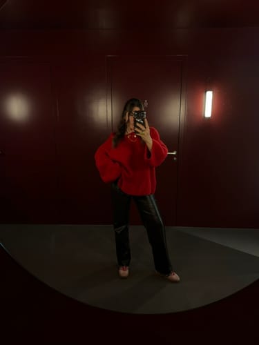 Kundin macht ein Spiegelselfie und trägt den weichen, roten Ultra-Soft Off-Shoulder-Strickpullover.