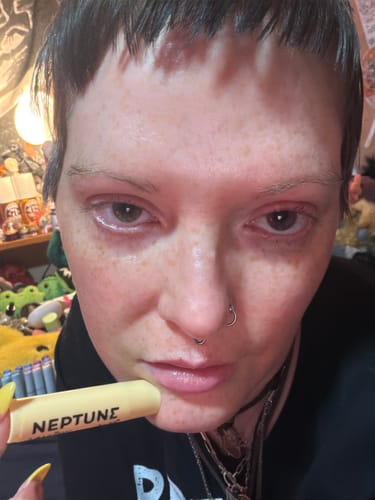 Close-up of a reviewer holding the Neptune Tallow & Manuka Honey Lip Balm near their lips.