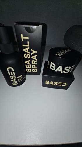 Reviewer's Sea Salt Spray bottle and its black packaging, shown next to another Based brand hair product.