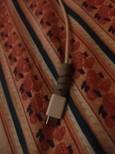 Close-up of a customer's grey cable protector wrapped around the end of a white charging cable.