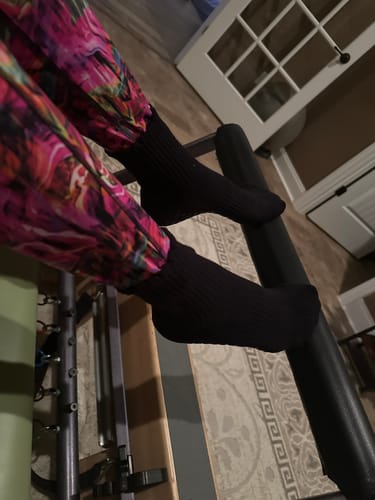 Customer wearing the black Elliosa Grip Basics socks with their feet resting on an exercise bar.