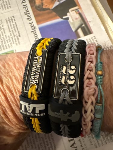 Customer's wrist wearing the black and yellow 'Keep Moving Forward' paracord bracelet among other bracelets.