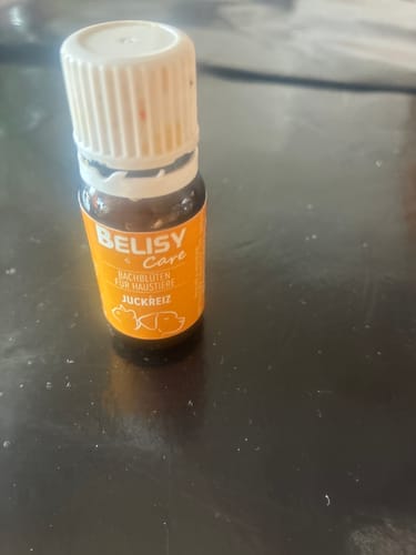 Ein Kunde zeigt das kleine Fläschchen der BELISY Bachblüten Globuli gegen Juckreiz auf einer dunklen Oberfläche.