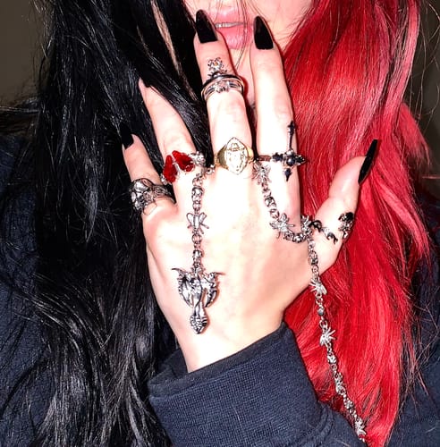 Customer's hand wearing the black Down Your Throat Ring on the middle finger, shown with other ornate jewelry.