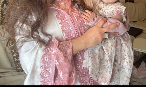 Close-up of a customer wearing the Jellaba Nadae in Pearl Pink, showing the detailed lace on the chest and sleeves.
