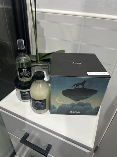 Reviewer's collection of OI products, including hair care and a decorative box, on a bathroom vanity.