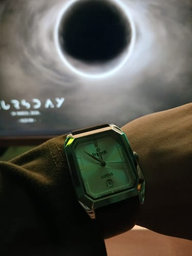 Reviewer wearing the square Sveston Lotus watch. The elegant dial glows in a dimly lit room.
