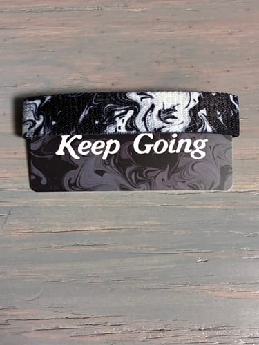Reviewer's black and white marbled Keep Going Interactive Bracelet shown on its matching display card.