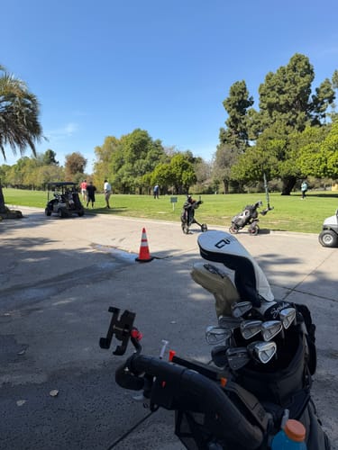 Customer's view from their Cybercart, showing their golf bag on a sunny course with other golfers.