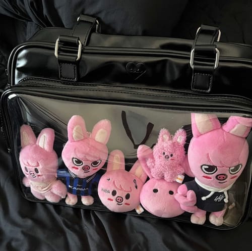 Customer's black COKO STAGE BAG holding several pink plush toys in its clear front pocket.