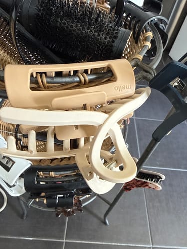 Customer's beige and off-white cloud clips resting in a basket filled with various hairbrushes.