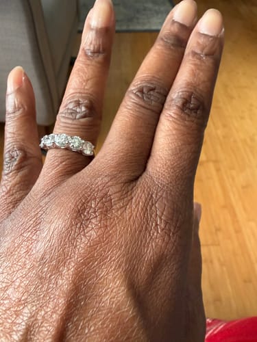 A customer's hand wearing the five-stone diamond anniversary band.