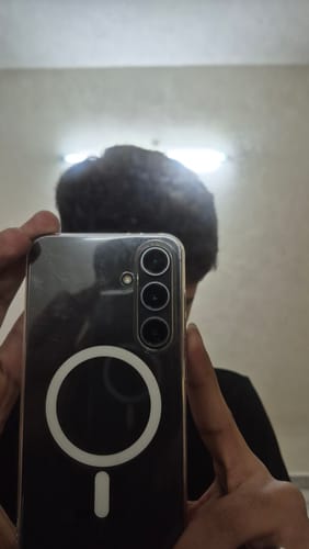 A reviewer takes a mirror selfie showing the back of their phone with the clear Anti Yellow Magsafe Case.