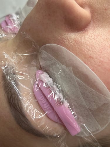 Close-up of a customer's lash lift, with a thick paste made from Pink Lash Lift Powder applied to lashes on a pink shield.