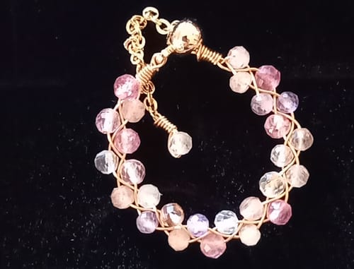 Photo d'un client montrant la bague Auralite 23 avec ses petites perles facettées roses et violettes sur fond noir.