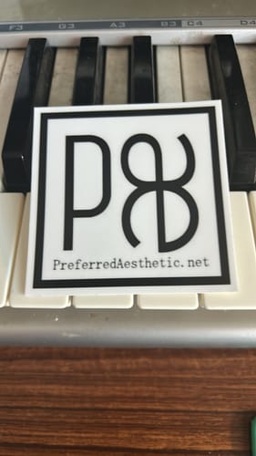 Customer's custom square vinyl sticker with a black border and logo, placed on piano keys.