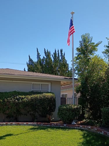 Customer's satin Ultra Heavy-Duty Home Flagpole installed in their front yard, flying the American flag.