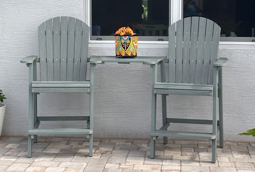 Customer's gray Counter Height Bistro Tete-a-tete set up on a stone patio in front of a window.