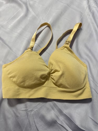 Customer's yellow Lovemère Seamless Nursing Bra laid flat on a bed, showing its seamless design and nursing clasps.