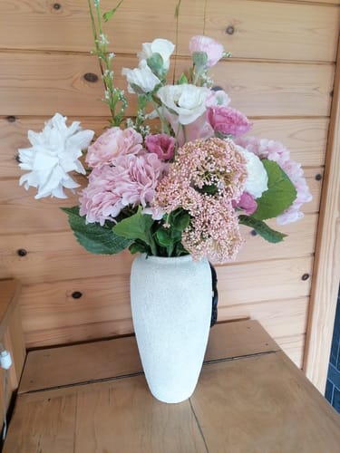 Klant toont het Boeket Jade in een witte vaas op een houten tafel.