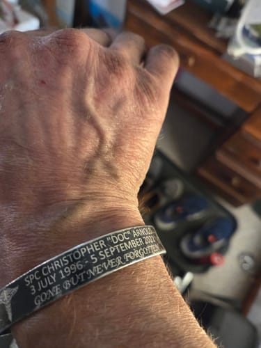 Close-up of a reviewer wearing the engraved SPC Christopher 'DOC' Arnold Memorial Band on their wrist.