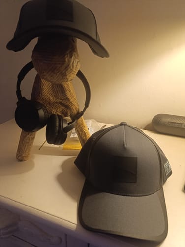 Recensent toont de grijze Core Collection Cap op een bureau, met een tweede pet op de achtergrond.
