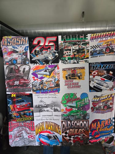 Customer holding up their finished Project Repat T-Shirt Quilt made from colorful auto racing shirts.