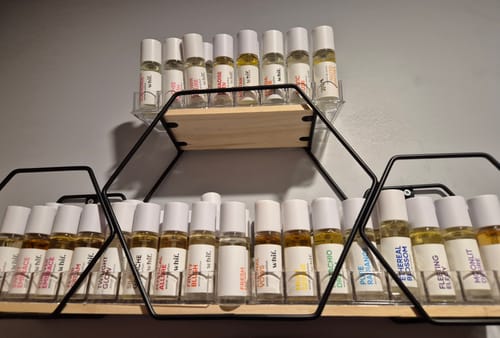 Reviewer's collection of many roll-on perfumes organized on a black, geometric shelf.