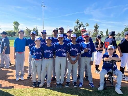 Customer's youth baseball team posing in their custom royal blue and white baseball uniforms on a field.