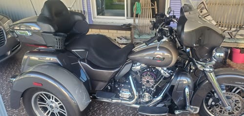 Customer's black Wind Rider Seat Cover installed on a large, grey trike motorcycle parked under a carport.